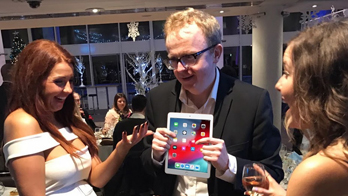 NOEL QUALTER entertains two women with iPad magic at a Christmas party