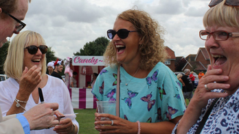 NOEL QUALTER makes three women laugh with iPad magic at a large outdoor event