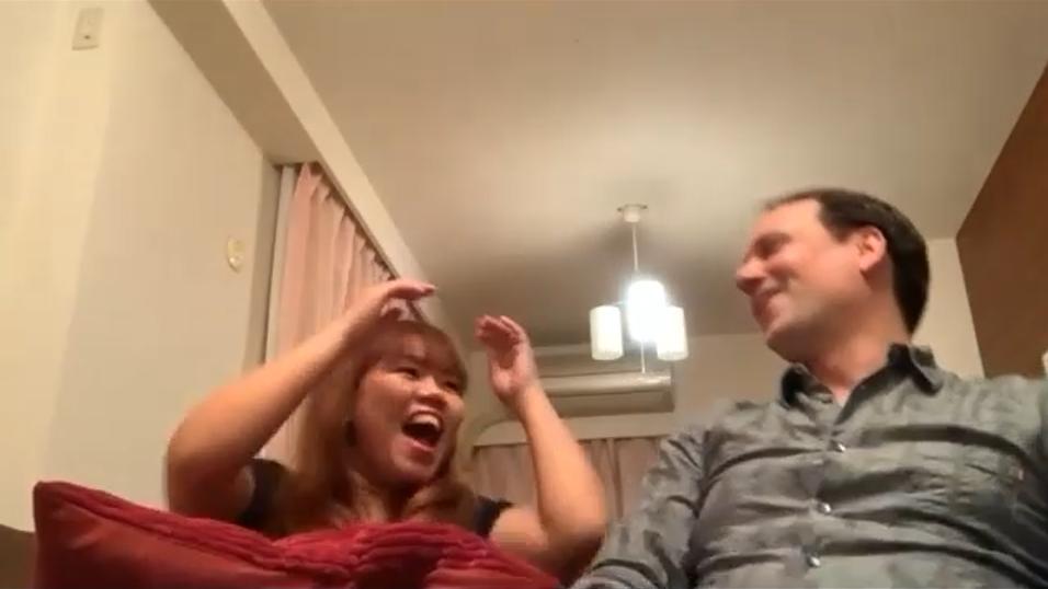 An amazed woman throws her arms in the air in amazement at one of Noel's online magic tricks